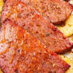 Hot honey glazed ham steaks roasted with pineapple slices on a sheet pan on a marble countertop
