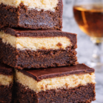 Stacked Irish spiked brownies with rich chocolate layers, creamy Irish cream filling, and glossy whiskey glaze on a light marble background.