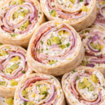 stacked italian grinder pickle dip pinwheel sandwiches with ham salami capicola and red onion slices