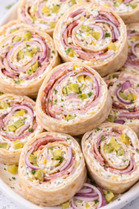 stacked italian grinder pickle dip pinwheel sandwiches with ham salami capicola and red onion slices