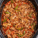 Italian pulled pork with peppers and onions in a slow cooker with tomato sauce