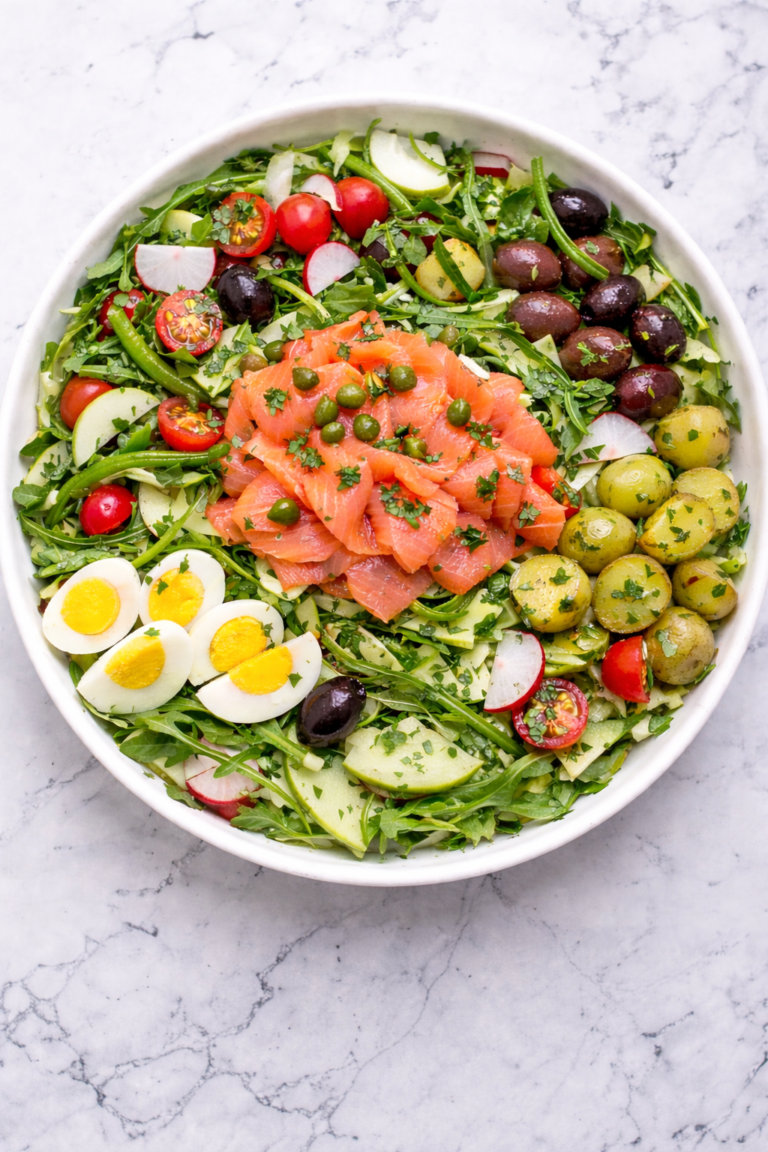 Lox Nicoise style salad with smoked salmon, potatoes, olives, green beans, tomatoes and eggs in a round white bowl