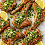 pan seared lamb chops with Greek garlic pesto on parchment paper with lemon and rosemary overhead view