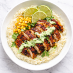 Peruvian chicken mashed potato bowl topped with sliced pollo a la brasa chicken and creamy aji verde sauce in a white bowl on a marble counter
