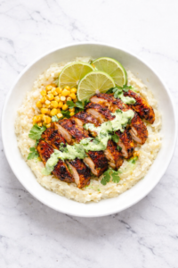 Peruvian chicken mashed potato bowl topped with sliced pollo a la brasa chicken and creamy aji verde sauce in a white bowl on a marble counter