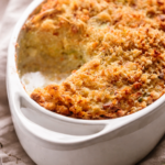 Creamy potato and leek gratin baked with Parmesan breadcrumbs in a white ceramic baking dish