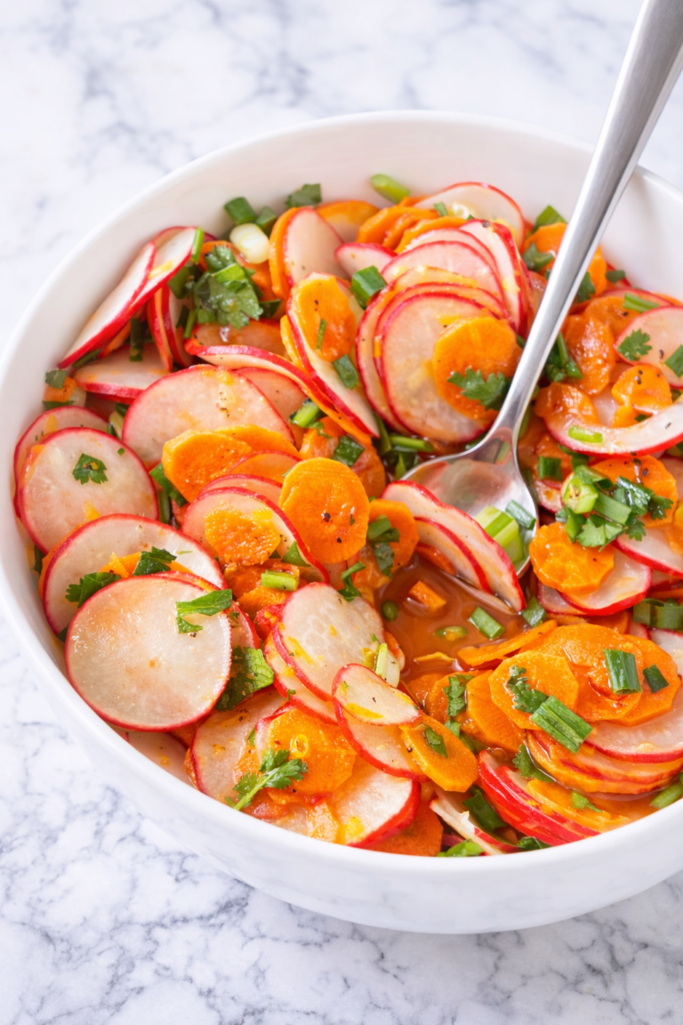 Radish carrot cilantro salad in a white bowl on a marble countertop with fresh citrus dressing