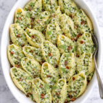 creamy ricotta pea pesto stuffed shells with bacon in white baking dish on marble counter