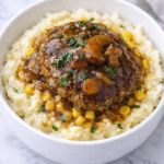 Salisbury steak mashed potato bowl with corn and onion gravy in a white bowl on a marble counter