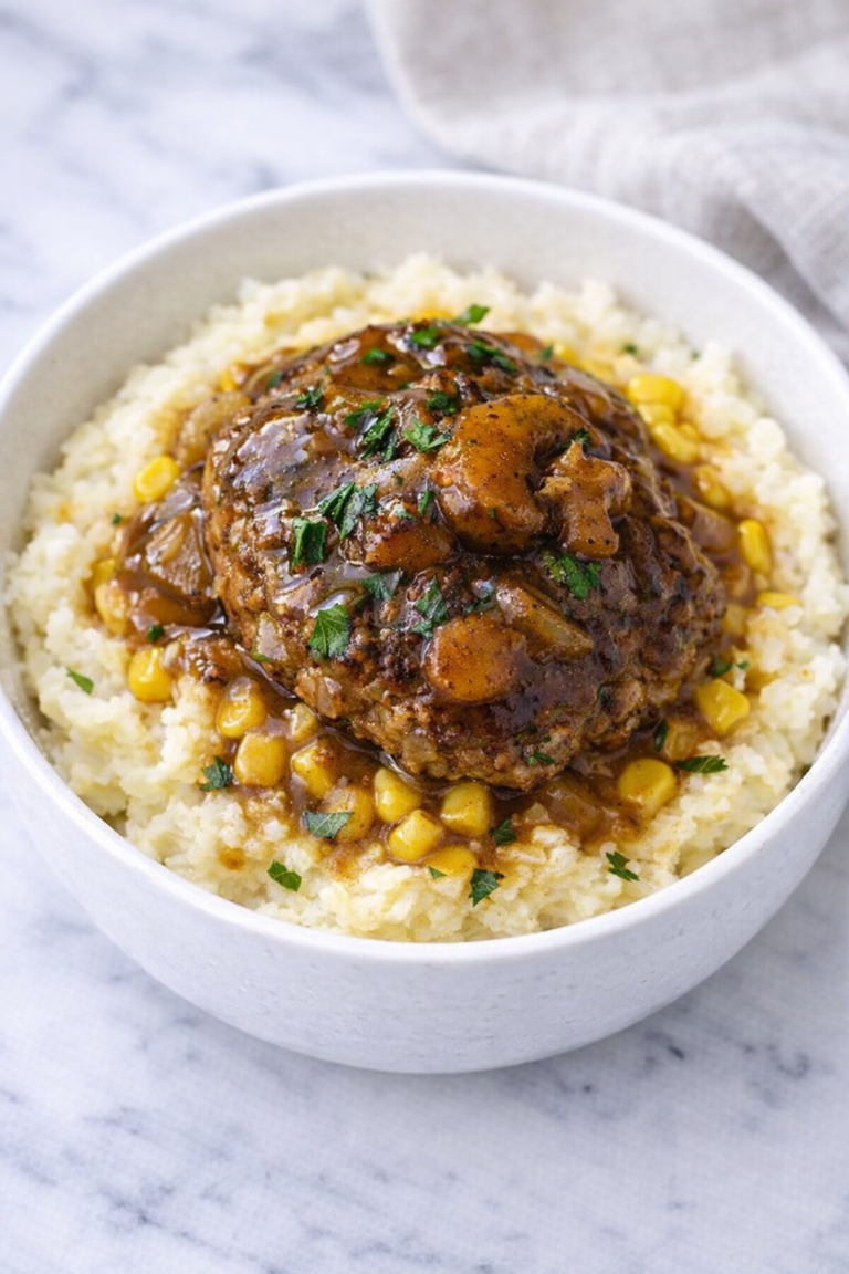 Salisbury steak mashed potato bowl with corn and onion gravy in a white bowl on a marble counter