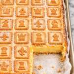 Sheet pan chessman pie bars topped with chessman butter cookies and dusted with powdered sugar on a marble countertop