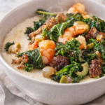 Shrimp, sausage, and kale served over creamy fontina cheese grits in a neutral bowl on a marble countertop.
