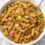Southern style green beans with bacon and onions in a white bowl on a marble countertop