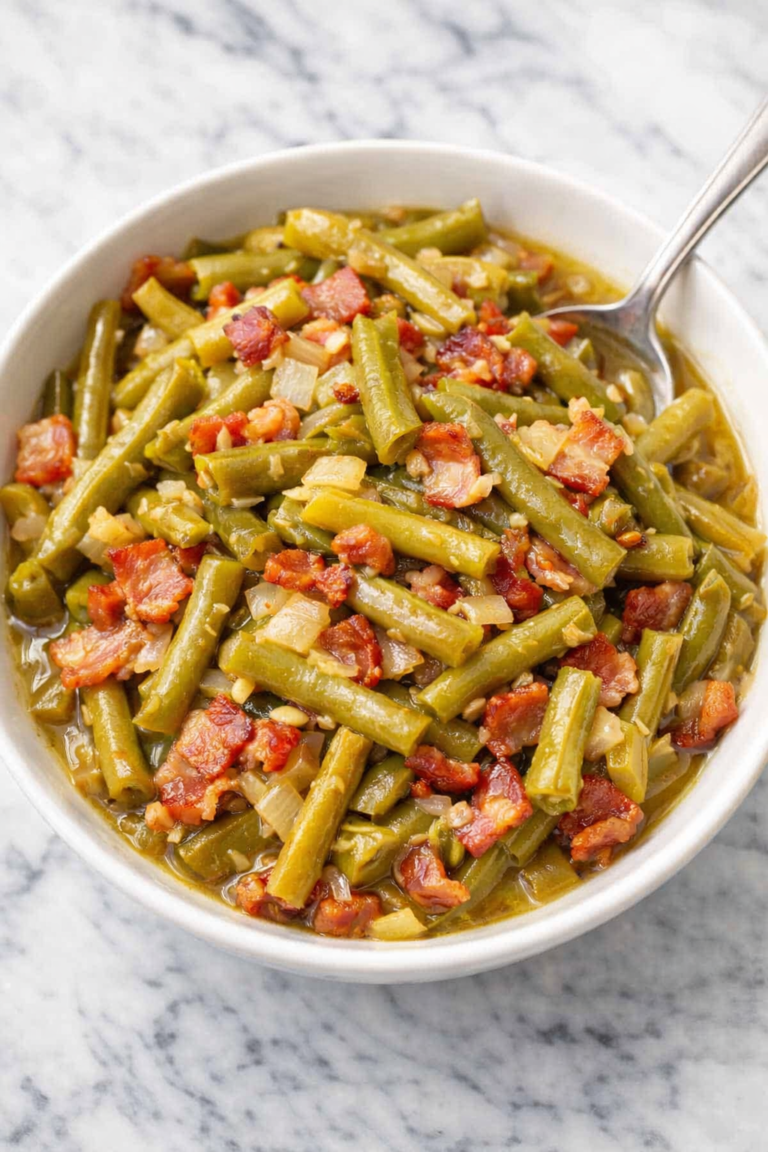 Southern style green beans with bacon and onions in a white bowl on a marble countertop