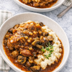 stout braised chicken with mushrooms served over mashed potatoes in a bowl with rich beer gravy