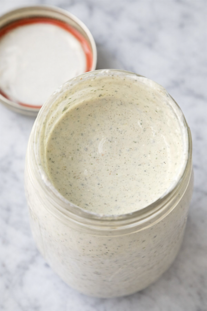 Homemade Sweet Tomatoes homestyle ranch dressing in a glass jar on a white marble countertop