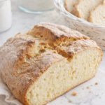 Traditional Irish soda bread loaf sliced on marble countertop with rustic golden crust and soft crumb