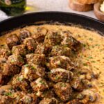 whiskey marinated steak tips in creamy garlic paprika sauce with mushrooms in a cast iron skillet