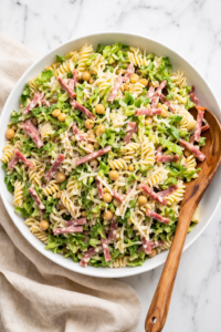 La Scala chopped pasta salad with rotini, salami, chickpeas, romaine, and pecorino in a white bowl on marble counter