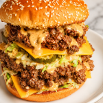 Big Mac sloppy joes stacked high on sesame seed buns with melty cheese, lettuce, pickles, and special sauce on a white plate