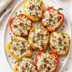 Chicken bacon ranch stuffed peppers topped with crispy bacon, ranch drizzle, melted cheese, and chives