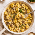 Garlic butter beef tortellini skillet with cheesy tortellini and ground beef in a creamy buttery sauce on a marble countertop with a fork lifting a bite
