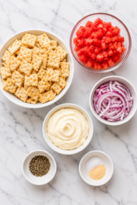 Flat lay of ingredients for Southern cracker salad including buttery crackers, tomatoes, red onion, mayonnaise, and seasonings