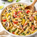 Creamy southwest fajita pasta salad with grilled chicken, black beans, corn, peppers, tomatoes, and rotini pasta in a white serving bowl on a marble countertop.