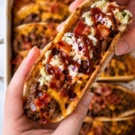 Western BBQ cowboy burger taco topped with coleslaw, crispy bacon, melted cheddar cheese, and barbecue sauce drizzle.