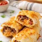 Stack of homemade ground beef taco hot pockets filled with seasoned taco meat and melted cheddar cheese on a white marble countertop.