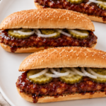 Homemade copycat McDonald's McRib sandwiches on a white oval platter topped with BBQ sauce, pickles, and sliced onions.