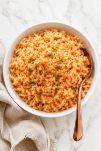 Copycat Texas Roadhouse seasoned rice served in a white bowl with a copper spoon on a white marble countertop and neutral linen towel.