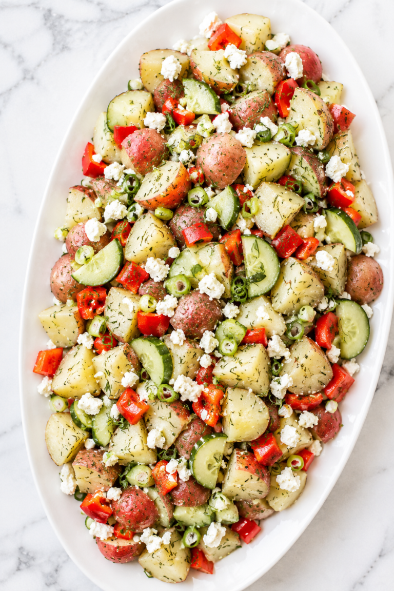 Fresh dill potato salad with feta cheese, red potatoes, cucumber, bell pepper, and scallions served on a white platter.