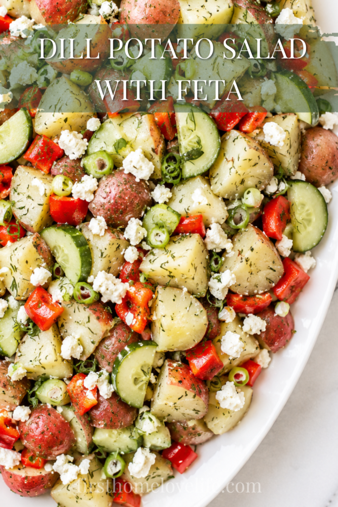 White platter filled with dill potato salad made with red potatoes, cucumber, red bell pepper, scallions, and crumbled feta cheese on a marble countertop.