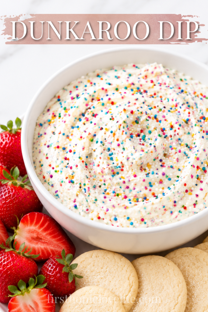 Creamy homemade Dunkaroo dip topped with rainbow sprinkles in a white bowl, served with soft sugar cookies and fresh strawberries on a marble countertop.