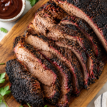 Juicy smoked brisket sliced on a wooden cutting board with a dark bark and smoky smoke ring, served on a white marble countertop.