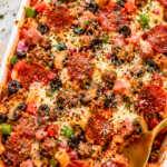Cheesy Supreme Pizza Pasta Bake Casserole with pepperoni, sausage, Canadian bacon, mushrooms, black olives, bell peppers, marinara sauce, and melted mozzarella cheese in a white casserole dish.