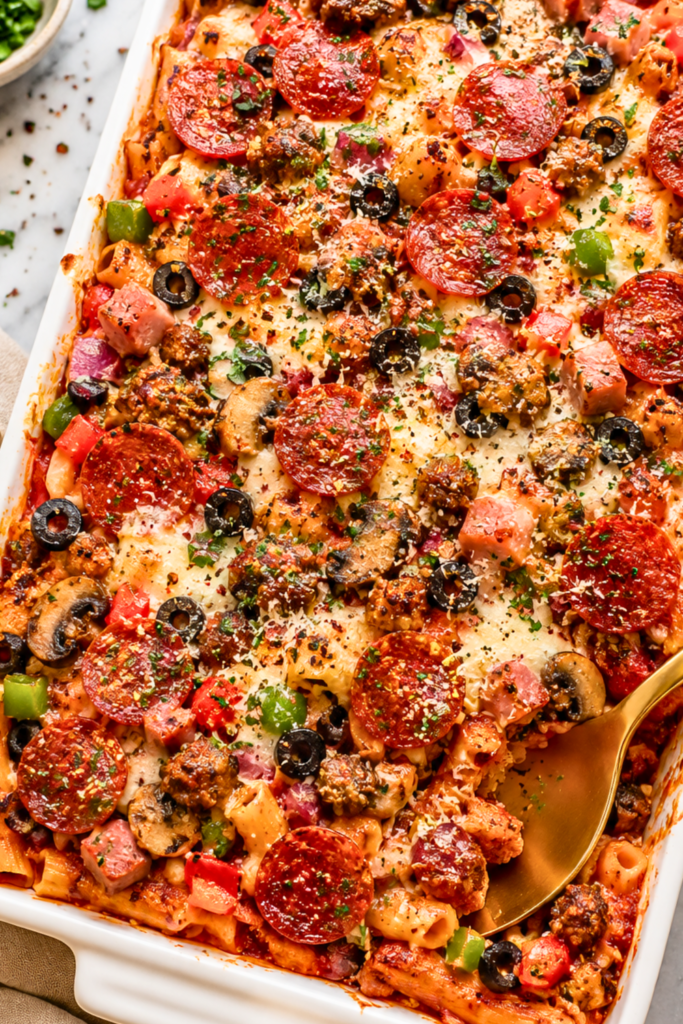 Cheesy Supreme Pizza Pasta Bake Casserole with pepperoni, sausage, Canadian bacon, mushrooms, black olives, bell peppers, marinara sauce, and melted mozzarella cheese in a white casserole dish.