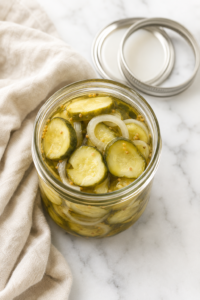 Open mason jar filled with homemade bread and butter pickle slices and onions in a sweet and tangy brine.