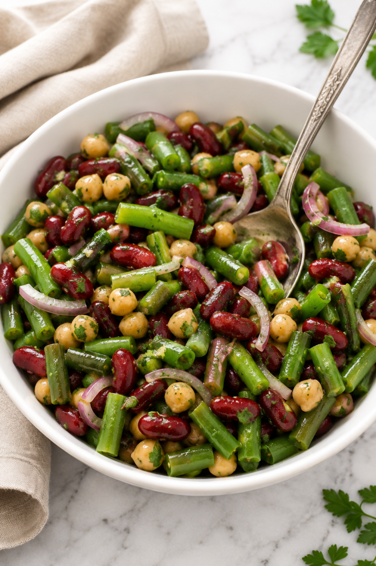 Classic green bean and bean salad with kidney beans, chickpeas, green beans, and red onion in a white serving bowl with a tangy homemade dressing.