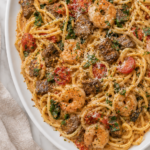 Creamy Copycat Olive Garden Calabrian Steak and Shrimp Bucatini with tomatoes and spinach on a white platter