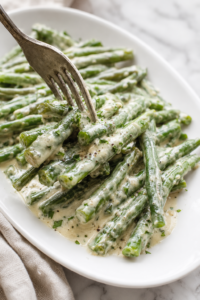 Fork lifting creamy Boursin green beans coated in garlic and herb cheese sauce
