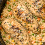 Three whole chicken breasts served over creamy crockpot rice with peas, carrots, corn, and savory onion gravy.