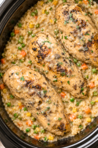 Three whole chicken breasts served over creamy crockpot rice with peas, carrots, corn, and savory onion gravy.