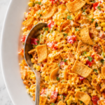Easy corn chip salad with sweet corn, cheddar cheese, red bell pepper, creamy dressing, and crunchy whole Fritos on a white platter.