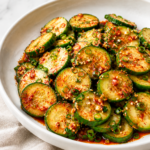 Easy cucumber kimchi with crisp sliced cucumbers, spicy gochugaru dressing, green onions and sesame seeds