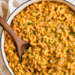 Easy homemade one-pan cheeseburger Hamburger Helper with ground beef, elbow macaroni, and creamy cheddar cheese sauce in a white enamel pot.