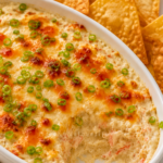 Hot crab rangoon dip topped with sweet chili sauce and scallions with crispy wonton chips for dipping.