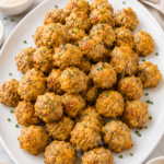 Easy homemade sausage balls served on a large white oval platter with dipping sauces and fresh chopped chives on a marble countertop.