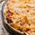 Creamy baked macaroni with stewed tomatoes and a golden breadcrumb topping in a rustic skillet.